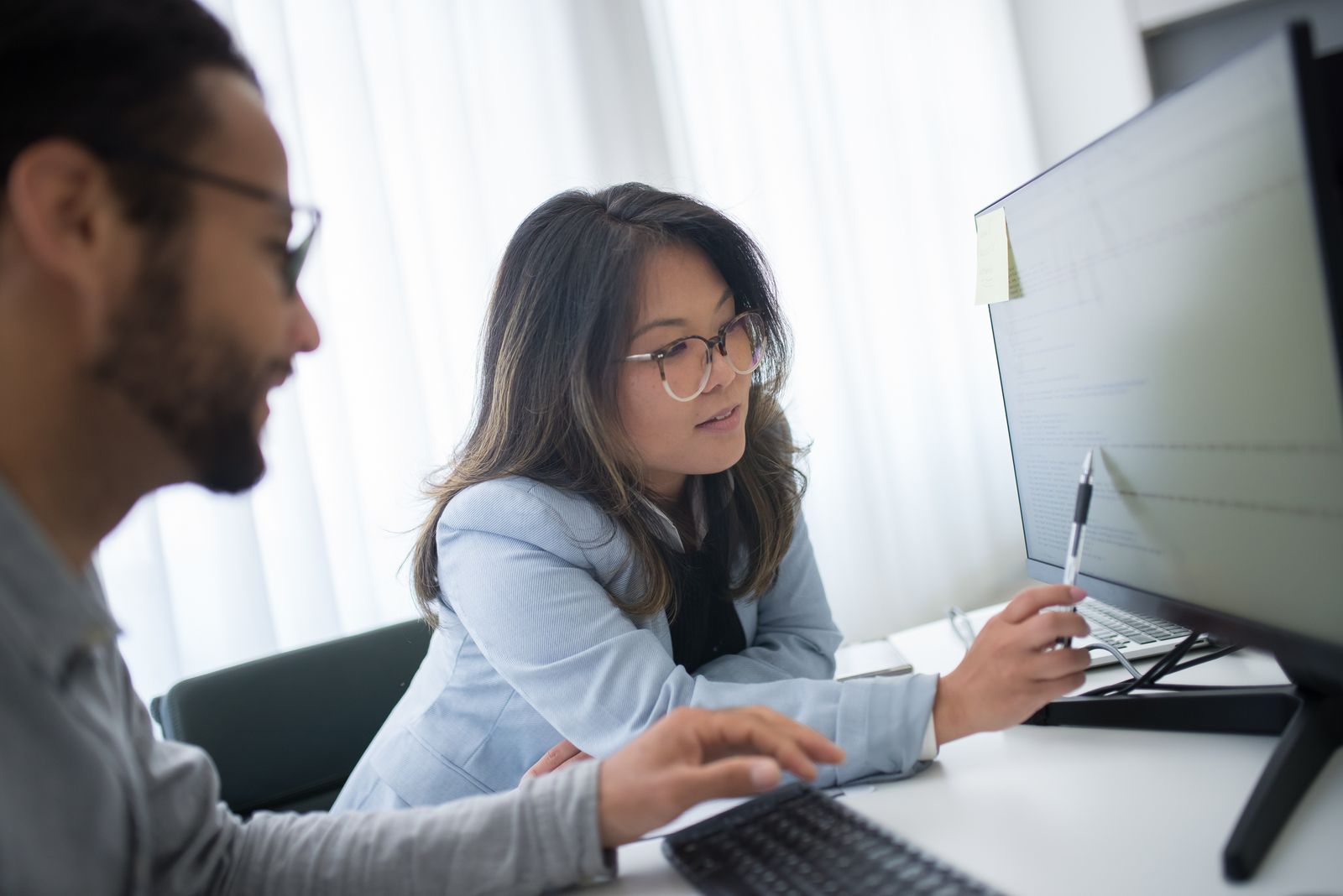 Two colleagues working through a problem together at a screen